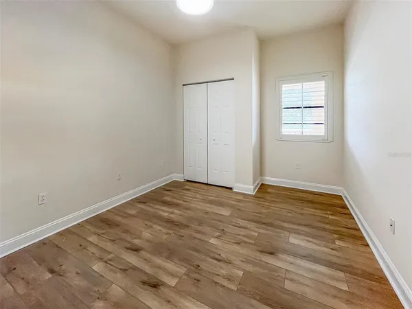 a view of empty room with wooden floor and fan