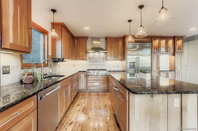 a kitchen with stainless steel appliances granite countertop a stove a sink and a refrigerator