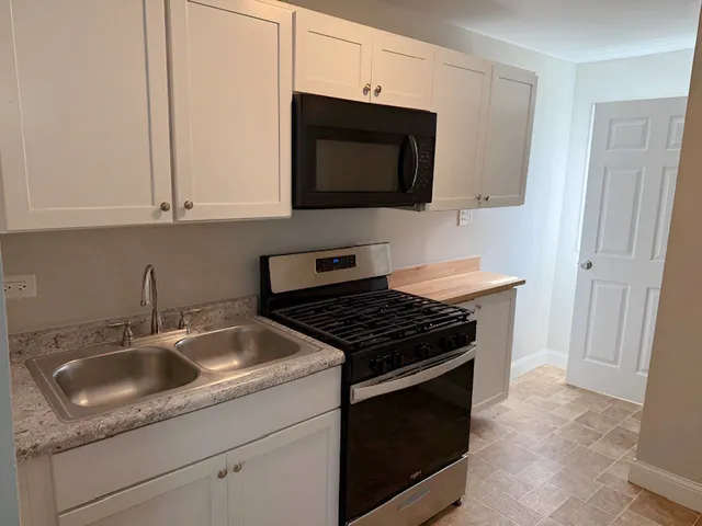 a kitchen with granite countertop white cabinets stainless steel appliances and sink