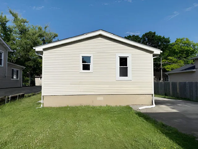 a view of backyard of house with wooden fence