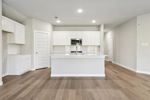 a view of kitchen with granite countertop white cabinets and stainless steel appliances