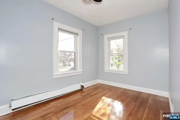 a view of a hallway with wooden floor and a refrigerator