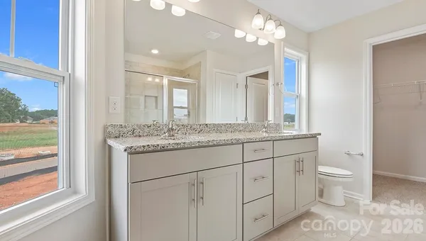 a bathroom with a granite countertop double vanity sink a mirror and a toilet