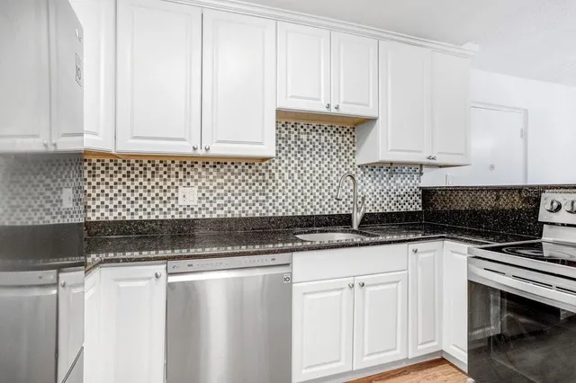 a kitchen with granite countertop white cabinets and sink