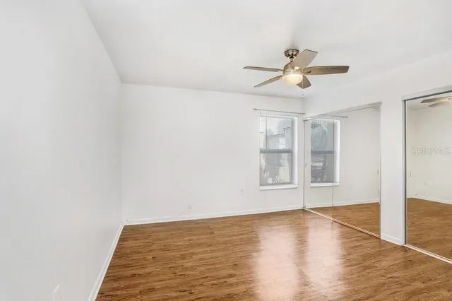 a view of empty room with wooden floor and fan