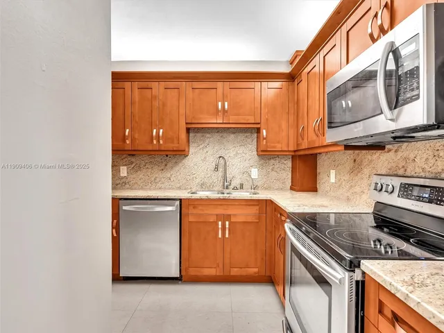 a kitchen with stainless steel appliances granite countertop a refrigerator and a sink