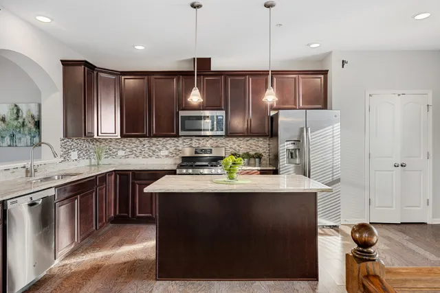 a kitchen with kitchen island granite countertop a sink stove and refrigerator