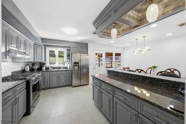 a kitchen with granite countertop lots of counter top space a sink and stainless steel appliances