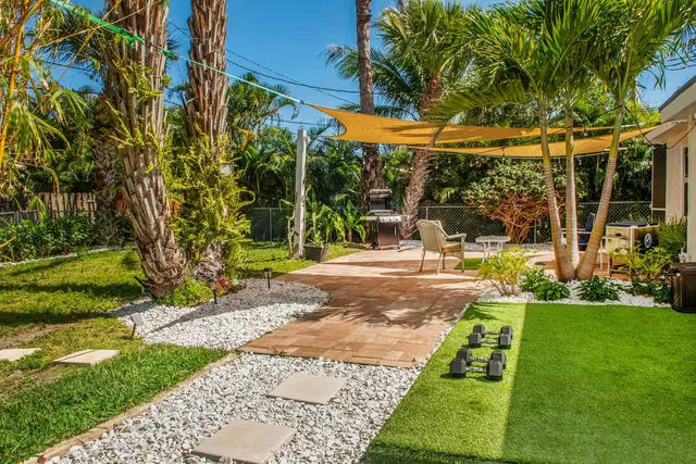 a view of a yard with plants and a table and chair
