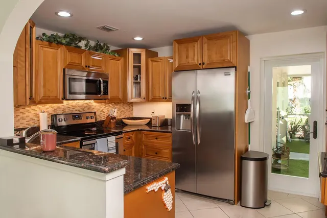 a kitchen with stainless steel appliances granite countertop a refrigerator a stove and a sink