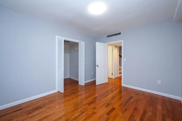 a view of an empty room with wooden floor and closet