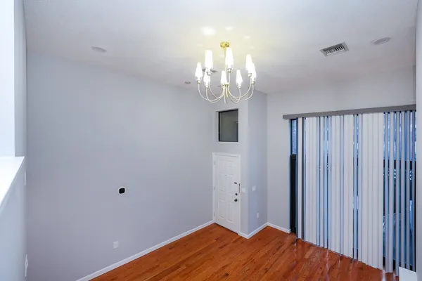 a view of a hallway with wooden floor and chandelier