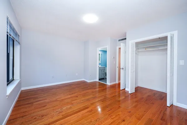 a view of an empty room with wooden floor and a window