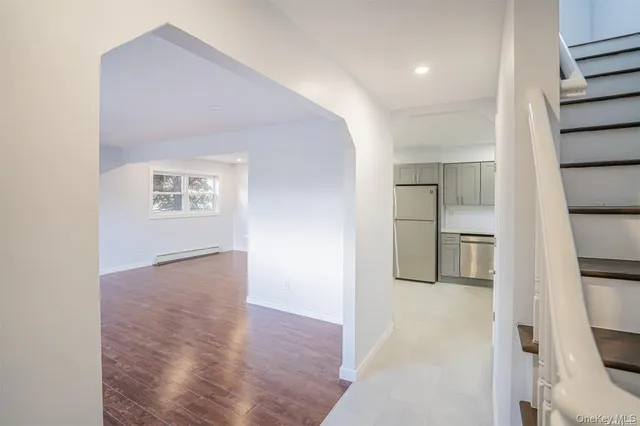 a view of empty room with wooden floor and kitchen
