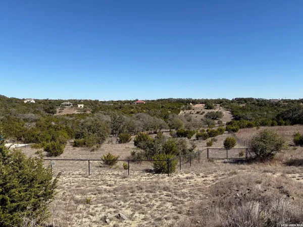 a view of a dry yard with wooden fence