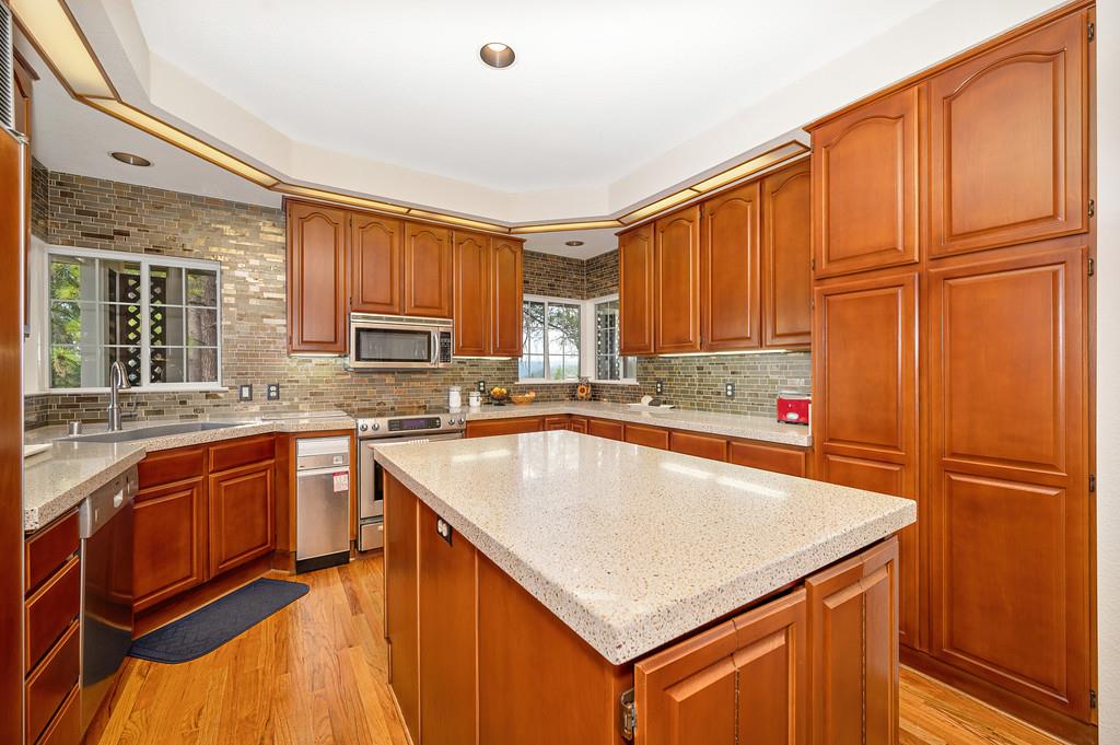 2358 Deer Ravine Court Cool, CA 95614 - Photo 7 of 63 kitchen with a center island, light wood-style flooring, wood finish cabinets, and stainless steel appliances