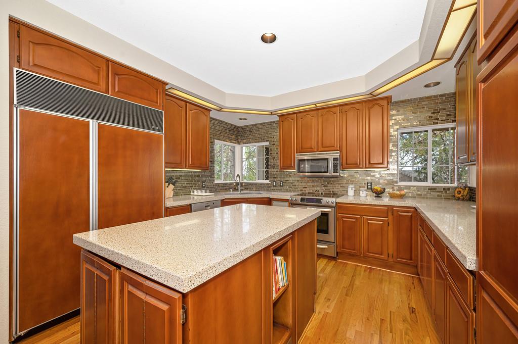 2358 Deer Ravine Court Cool, CA 95614 - Photo 8 of 63 kitchen featuring stainless steel appliances, light wood-style flooring, a kitchen island, and wood finish cabinetry