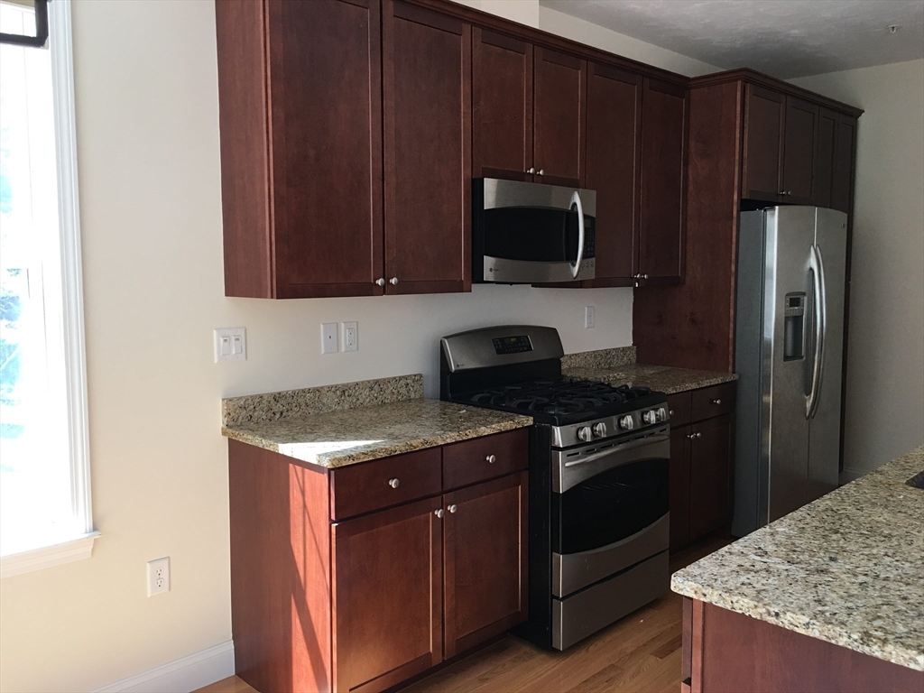 4 Reserve Way, Unit D Burlington, MA 01803 - Photo 5 of 17 a kitchen with a stove and a microwave