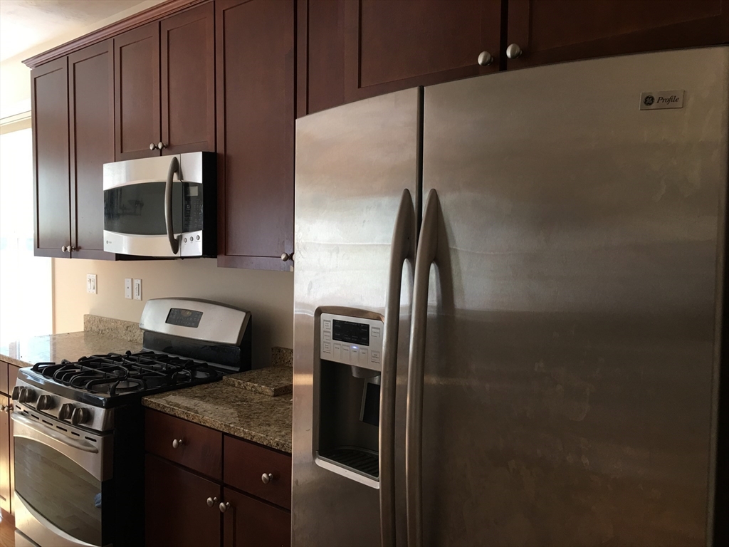 4 Reserve Way, Unit D Burlington, MA 01803 - Photo 6 of 17 a kitchen with granite countertop a refrigerator stove and microwave