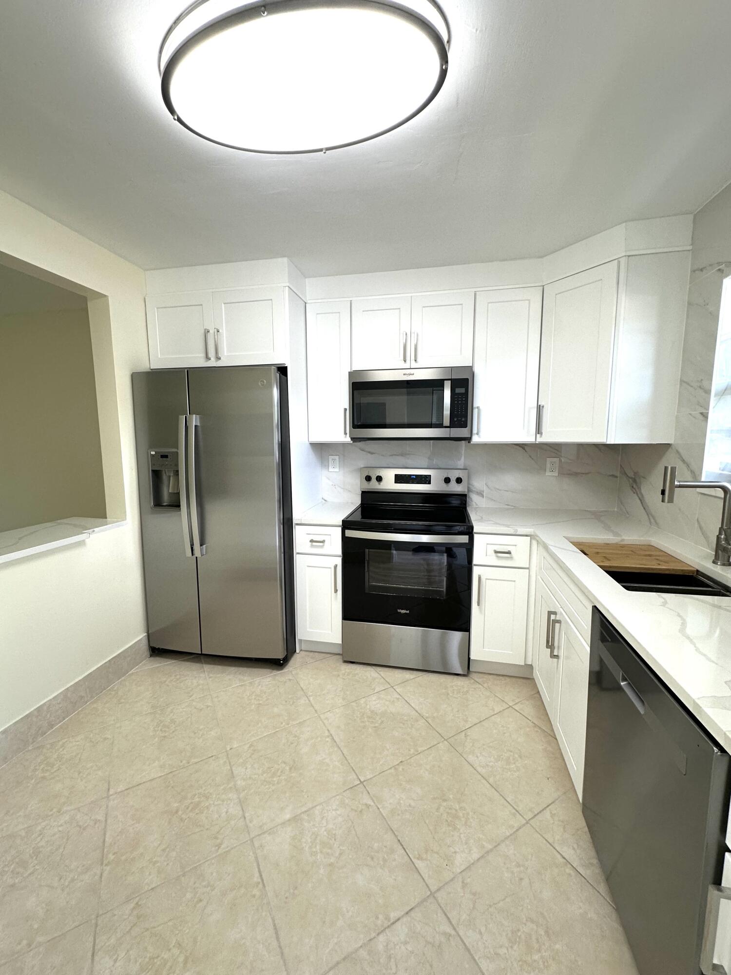 9440 Southwest 8th Street, Unit 109 Boca Raton, FL 33428 - Photo 2 of 14 a kitchen with stainless steel appliances a refrigerator a stove a sink and a microwave