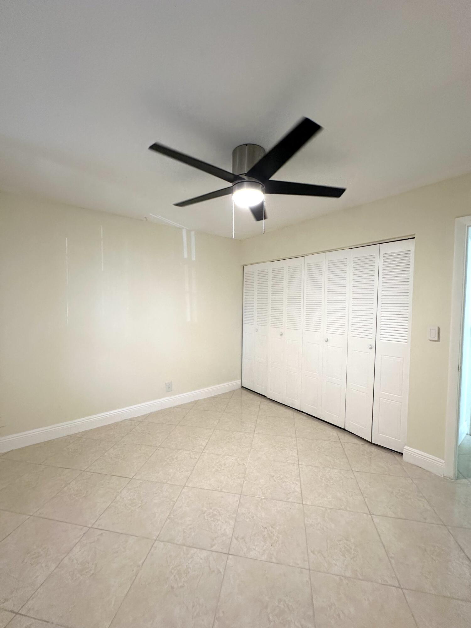 9440 Southwest 8th Street, Unit 109 Boca Raton, FL 33428 - Photo 8 of 14 an empty room with a ceiling fan and carpet