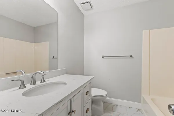 a bathroom with a granite countertop sink toilet and shower