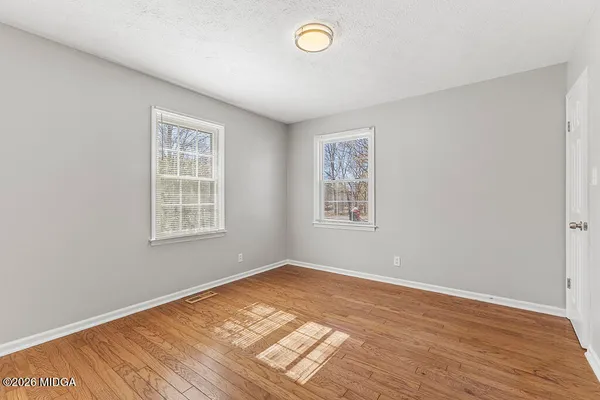 an empty room with wooden floor and windows