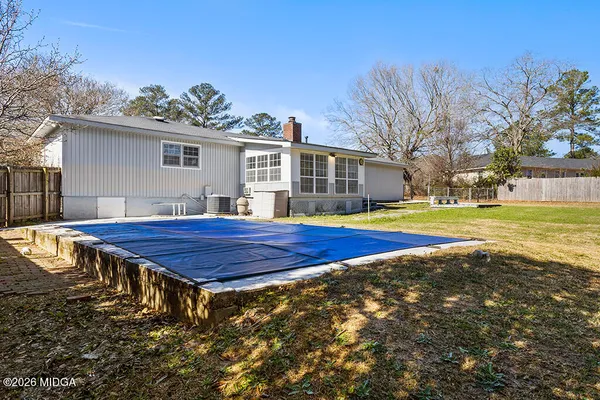 a view of pool with large trees and wooden fence
