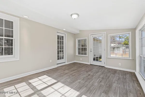 an empty room with wooden floor and windows