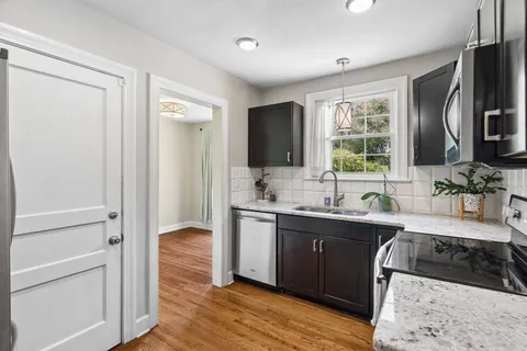 a large kitchen with stainless steel appliances granite countertop a sink stove and refrigerator