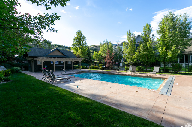 557 Craftsman Way Midway, UT 84049 - Photo 58 of 59 Outdoor swimming pool with concrete decking, surrounding green lawn, and a covered clubhouse featuring a pergola and dark-toned siding