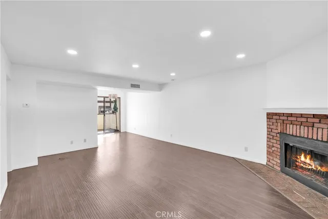 an empty room with wooden floor a fireplace and a window