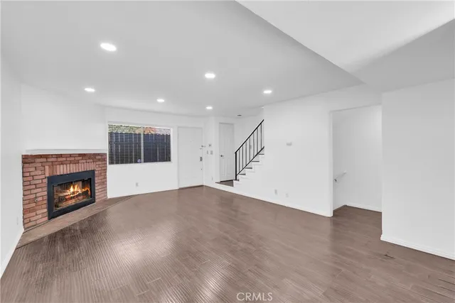 an empty room with wooden floor fireplace and windows