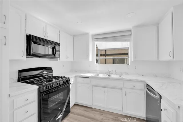 a kitchen with granite countertop a sink stove and microwave