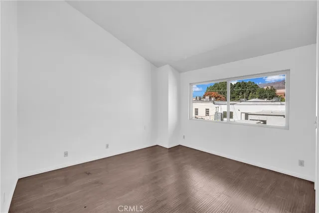 an empty room with wooden floor and outdoor view