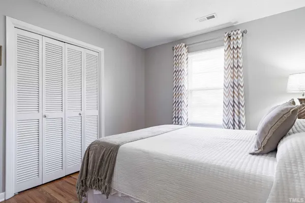 a bedroom with a bed a dresser and painting on the wall