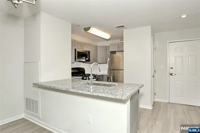 a kitchen with kitchen island granite countertop a sink stove and refrigerator