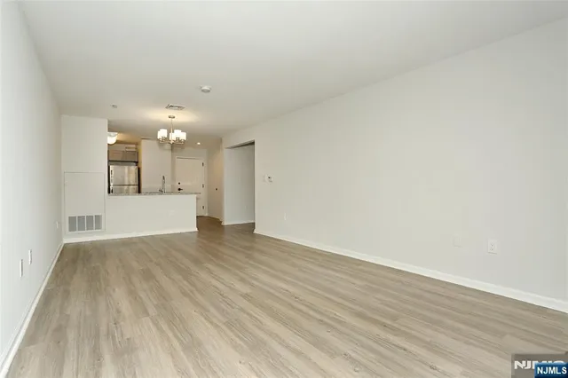 a view of a big room with wooden floor and a kitchen