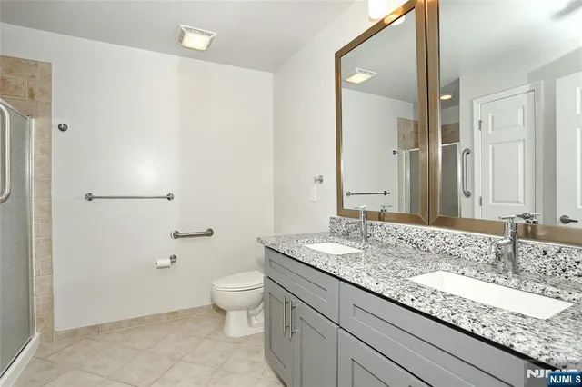 a bathroom with a granite countertop sink a toilet and shower