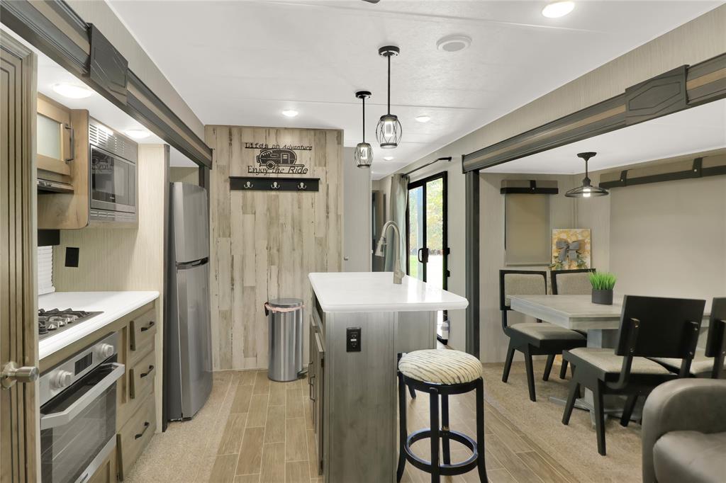 405 Broken Bow Quitman, TX 75783 - Photo 5 of 33 Kitchen with island, light countertops, hanging light fixtures, stainless steel appliances, 4 chair dining and recessed lighting