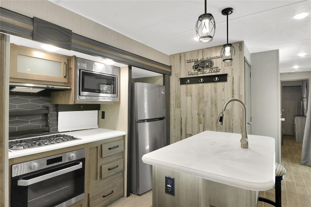 405 Broken Bow Quitman, TX 75783 - Photo 7 of 33 Kitchen featuring stainless steel appliances, wood floors, white countertops, hanging light fixtures, and a kitchen breakfast bar