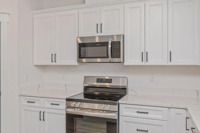 a kitchen with white cabinets and appliances