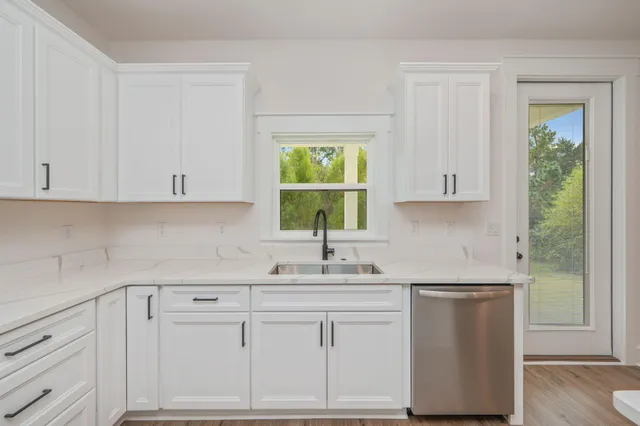 a kitchen with white cabinets and a window