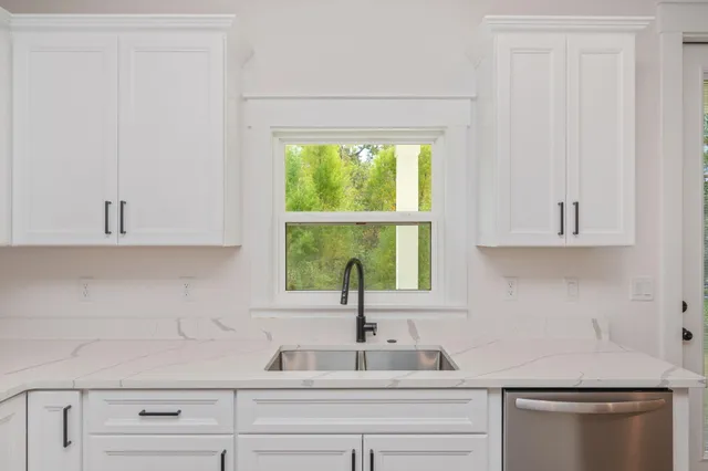 a kitchen with white cabinets and a window