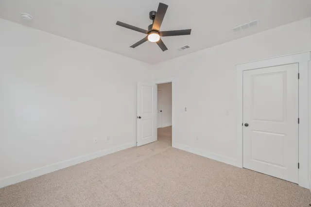 an empty room with windows and ceiling fan view