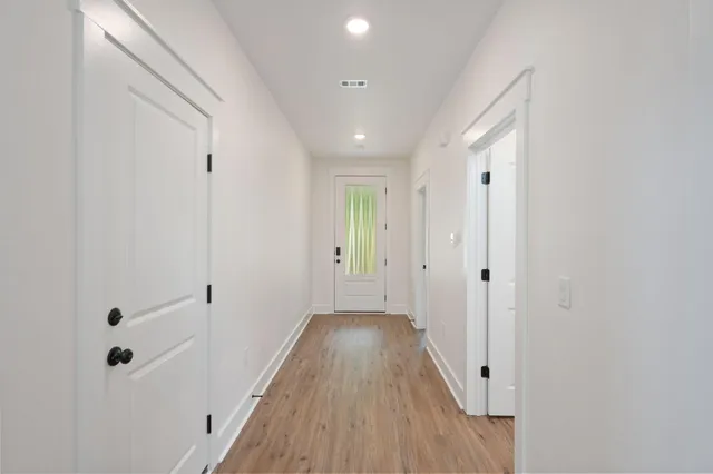 a view of a hallway with wooden floor and closet area