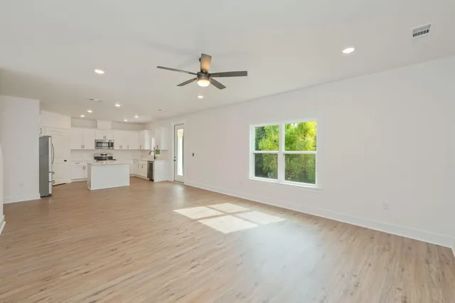 a view of an empty room with a window and kitchen view