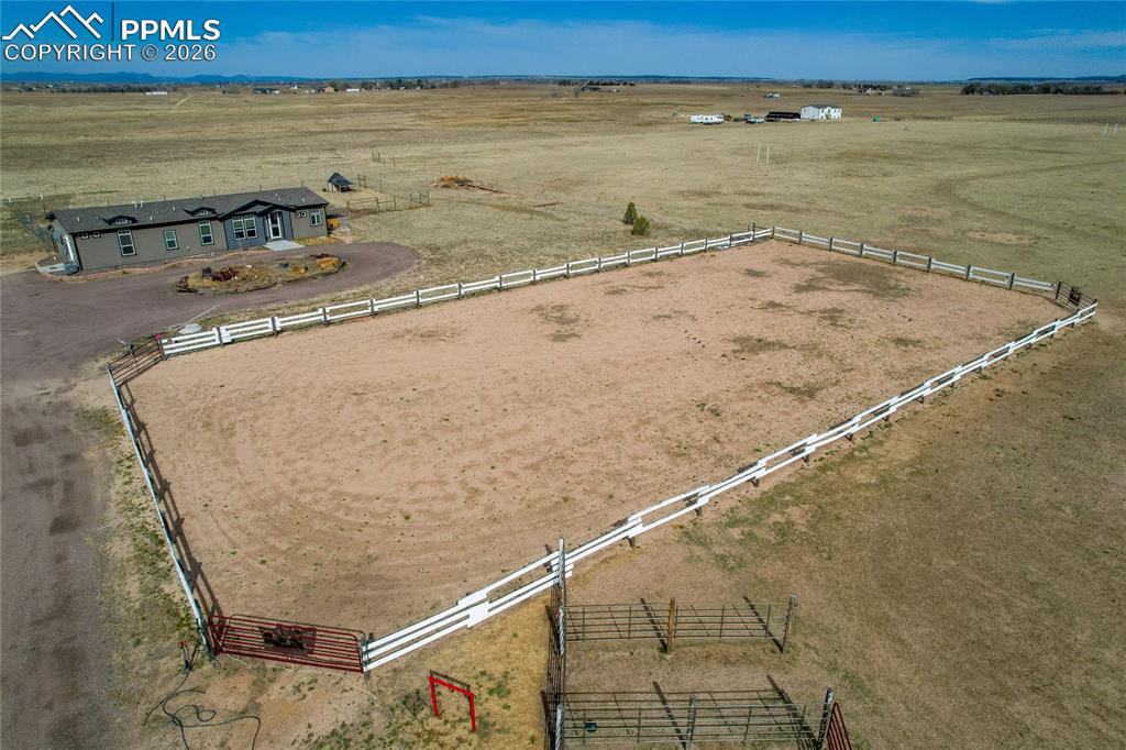 7880 J D Johnson Road Peyton, CO 80831 - Photo 35 of 50 Expansive fenced arena with white three-rail fencing and red metal gates