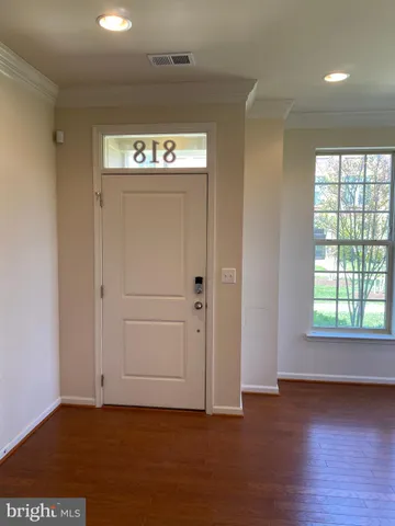 an entryway at an empty room with wooden floor and a window