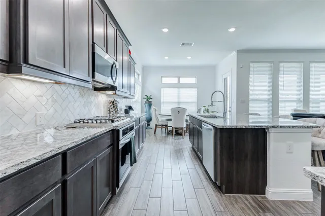 a kitchen with stainless steel appliances granite countertop a stove a sink and a microwave